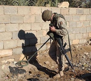 Um soldado do exército dos EUA utiliza um detector de metais para procurar armas e munições no Iraque